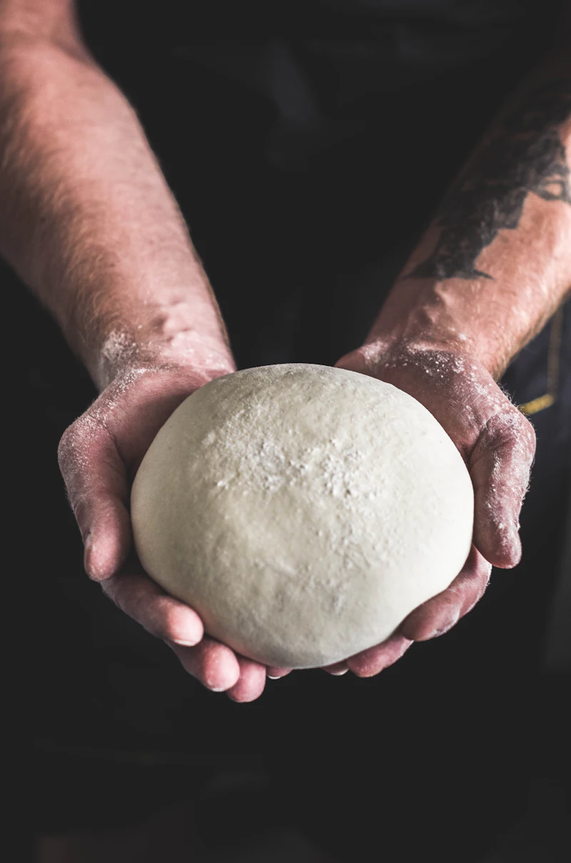 Boule de pâte tenue entre deux mains farinées